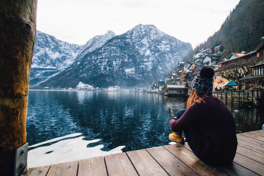 winter travel photo with woman sitting at a dock with a view of a mountain