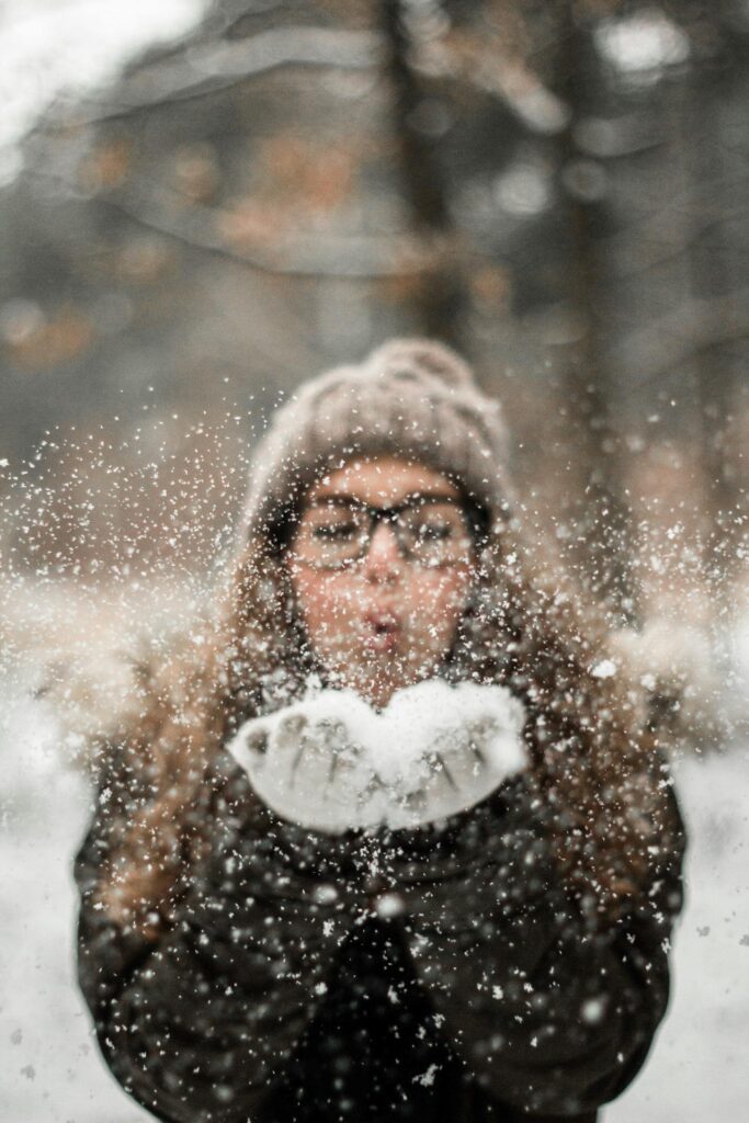 vrouw blaast sneeuw naar camera
