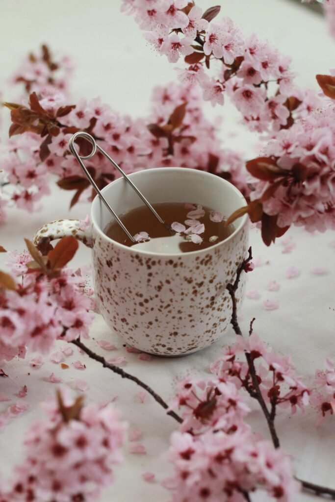 Tasse Tee, umgeben von rosa Blumen