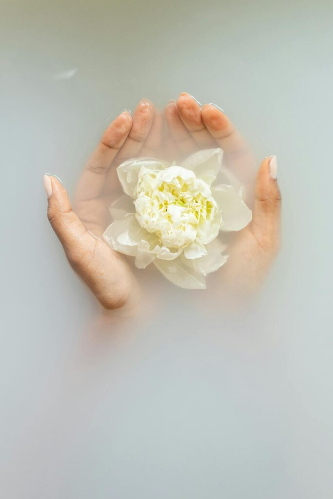 Blume in den Händen, in weiß gefärbtem Wasser